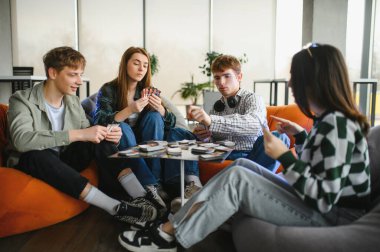 Dört genç yetişkin, rahat ve modern bir dairede oyun oynayarak boş zamanlarının tadını çıkarıyorlar.