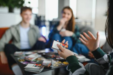 Bir grup arkadaş evde kağıt oynayarak eğleniyor, neşeli anılar yaratıyor ve dostluk bağlarını güçlendiriyor.