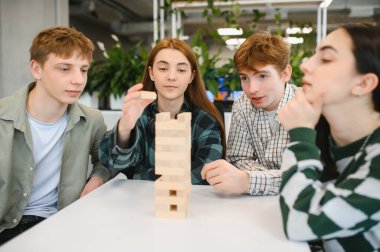 İş arkadaşları, modern bir ofis molasında kule bloğu oyunu oynarken birlikte eğleniyorlar.