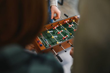 Neşeli iş arkadaşları masa futbolu oynuyor, ofiste birlikte eğleniyorlar.