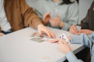 Bir grup arkadaş birlikte vakit geçirmenin tadını çıkarıyorlar. Masanın etrafında gülüp kart oynuyorlar. Sevimli anılar yaratıp bağ kuruyorlar.