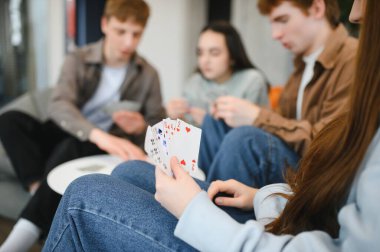 Bir grup arkadaş sıcak bir oturma odasında oyun oynuyorlar, kahkahaları paylaşıyorlar ve birlikte neşeli anılar yaratıyorlar.