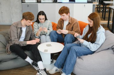 Dört meslektaş, rahatlık ve arkadaşlıkla dolu günlük ofis ortamında eğleniyor ve gülüyor.