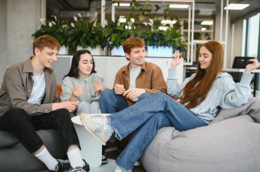 Yeni başlayan dört genç çalışan, modern bir çalışma alanında kart oynayarak tatillerini geçiriyorlar.