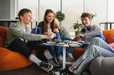 Sıradan bir ofis ortamında masa oyununda eğlenen bir grup genç iş arkadaşı takım çalışmasını ve arkadaşlığı teşvik ediyor.