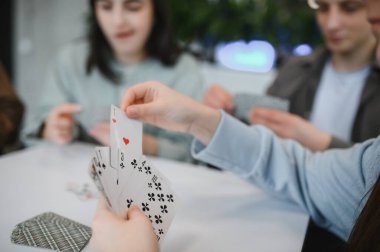 Mutlu arkadaşlar evde kağıt oynarken eğleniyorlar, kahkahalar atıyorlar ve rahat bir atmosferde kalıcı anılar yaratıyorlar.