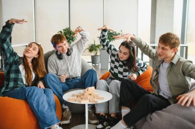 Dört genç yetişkin renkli puf minderlerde oturuyor, neşeli bir masa oyununun tadını çıkarıyor, kahkahalarını paylaşıyor ve birlikte neşeli anılar yaratıyorlar.