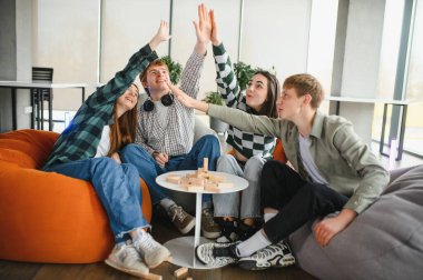 Dört neşeli öğrenci, zaferlerini kutlamak ve eğlenmek için evlerinde oyun oynadıktan sonra beşlik çakıyor.