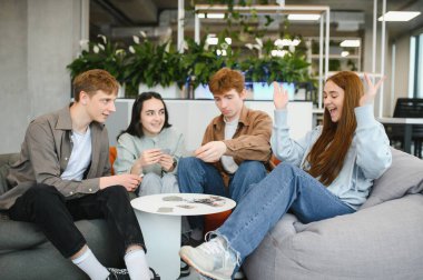 Çağdaş bir ofiste çalışma günlerine biraz eğlence katarak kağıt oyununun tadını çıkaran dört neşeli meslektaşımız.