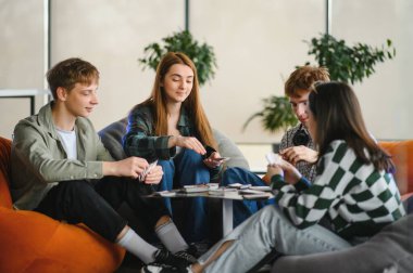 Dört arkadaş boş zamanlarının tadını çıkarıyorlar, rahat ve modern bir oturma odasında armut koltuklarda oturuyorlar.