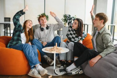 Dört neşeli arkadaş heyecan içinde ellerini kaldırarak büyüleyici bir masa oyunu oynuyorlar, birlikte eğleniyorlar ve eğleniyorlar.