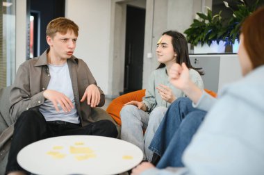 Mola sırasında eğlenen bir grup genç meslektaşın modern ofis alanlarında alınlarına yapışkan notlar yapıştırarak ben kimim oyunu oynuyorlar.