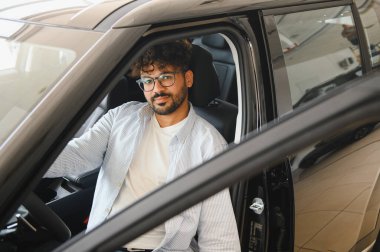 Şık, yeni bir arabada oturan mutlu müşteri, başarılı satın alımıyla gurur duyarken bayiliğin tadını çıkarıyor.