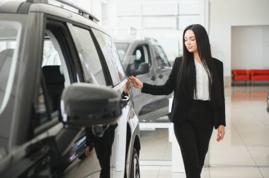 Modern bir araba galerisinde potansiyel bir müşteriye yeni bir araba sunan profesyonel bir satıcı.