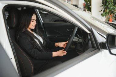 İş kadını yeni araç özelliklerini keşfediyor, araba galerisinde modern otomotiv teknolojisi deneyimliyor