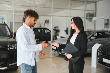 Satıcı kadın araba galerisindeki bir müşteriye araba anahtarlarını veriyor ve yeni bir araç satın alıyor.