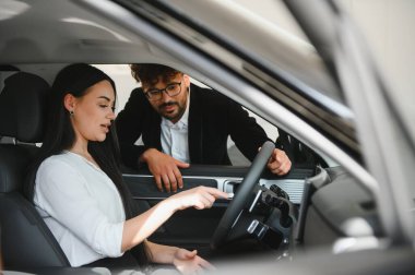 Satış elemanı müşteriye yeni araç seçmesinde yardımcı oluyor, araba özelliklerini ve işlevlerini otomobil içinde açıklıyor
