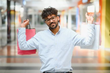 Alışveriş torbaları gösteren, alışveriş merkezlerinde alışveriş yapan, satış yapan ve indirim yapan mutlu bir Arap.