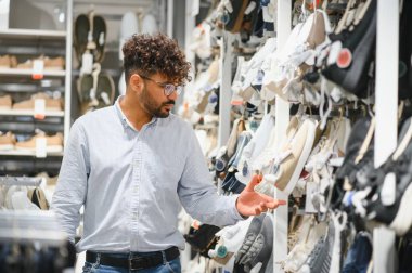 Sakallı Arap müşteriler, hareketli bir moda alışveriş merkezinde geniş bir şık ayakkabı seçimine göz atıyorlar, çeşitli seçenekler üzerinde düşünüyorlar.