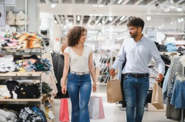 Alışveriş torbalarıyla gezen ve alışverişlerinin keyfini çıkaran mutlu bir çift.