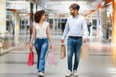 Arap çift canlı alışveriş cümbüşünden zevk alıyor, hareketli alışveriş merkezlerinde dolaşırken canlı çantalar taşıyorlar, gülücükler ve kahkahalar atıyorlar.