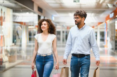 Gülümseyen Arap çift alışveriş merkezlerinde alışveriş torbaları taşıyor, birlikte boş zamanlarının tadını çıkarıyorlar.
