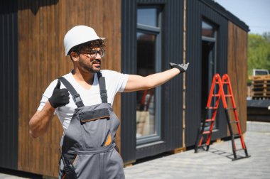 İnşaat işçisi prefabrik evin kamyonete yerleştirilmesini koordine ediyor, güvenli ve verimli ulaşımı sağlıyor.