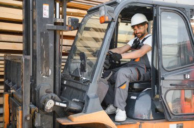 Kereste deposunda forklift manevrası yapan usta işçiler uzmanlık ve verimlilikle keresteleri yönetir.