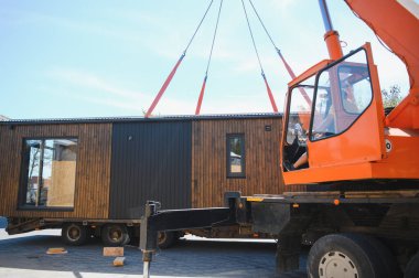 Vinç operatörü prefabrik modüler evi kamyona yüklüyor, verimli inşaat ve ulaşım yöntemleri sergiliyor