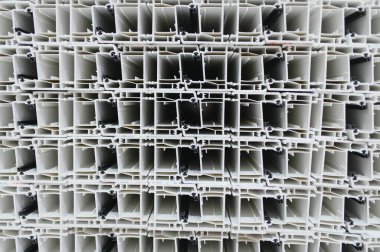 Birçok özdeş beyaz pvc pencere çerçeveleri düzenli olarak istiflenir, görsel olarak tekrarlayan bir desen oluşturur