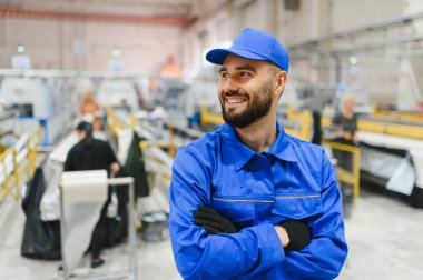 Modern bir fabrikada kolları çapraz duran gülümseyen bir fabrika işçisinin portresi pvc ve alüminyum pencere ve kapı yapımı için.
