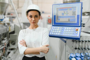 Çapraz kollu kendinden emin kadın mühendis, son teknoloji üretim tesisinde üretim sürecini denetliyor.