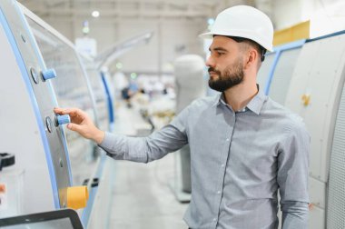 Endüstriyel mühendis, üretim hattındaki makine ayarlarını düzelterek, modern imalat fabrikasında sorunsuz işleme ve kalite kontrolünün sağlanmasını sağlıyor.