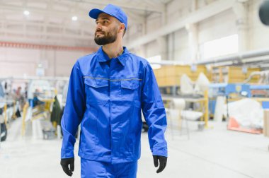 Üretim tesisinde yürüyen kendinden emin bir fabrika işçisi, düzgün bir çalışma ve yüksek kalitede pencere ve kapı imalatı sağlıyor.