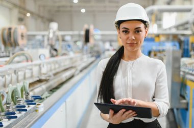 Modern PVC ve alüminyum pencere fabrikalarında üretim hattını incelerken dijital tablet kullanan kendine güvenen kadın mühendis.