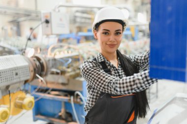 Modern bir imalat fabrikasında endüstriyel makineler çalıştıran kendine güvenen kadın fabrika işçisi, endüstriyel bir ortamda uzmanlık ve profesyonellik sergiliyor.