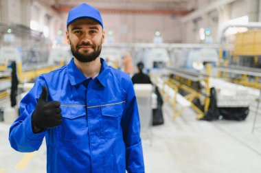 Kendine güvenen fabrika işçisi iyi niyet gösterisi yapıyor, modern bir pencere ve kapı üretim hattında çalışıyor, yüksek kaliteli ürünler temin ediyor.