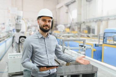 Tablet tutan üretim mühendisi alüminyum ve pvc pencere ve kapı fabrikalarında pencere profili ekstrüzyon çizgisi gösteriyor