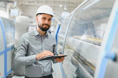 Modern fabrikadaki üretim hattını incelerken dijital tablet kullanan sanayi mühendisi.