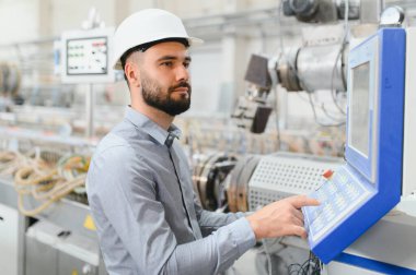 Modern fabrikada üretim sürecine odaklanan, sabit kasklı çalışan makineler takan endüstri mühendisi