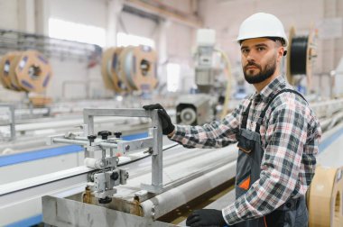 PVC pencere ve kapı imalatçısı fabrikasında, çelik başlık ve tulum giyen bir fabrika işçisi.