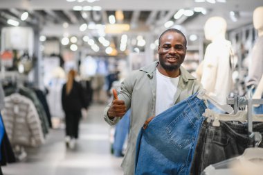 Bir giyim mağazasında yeni kot pantolon alırken, perakende terapi deneyiminin tadını çıkaran mutlu müşteri.