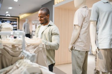 Müşteri, modaya uygun giyim mağazalarında şık kıyafetler seçerken hareketli bir alışveriş deneyimi yaşıyor.