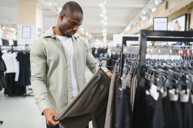 Afrika kökenli Amerikalı bir adam şık kıyafetler seçmeye odaklanmış. Moda tercihlerini ve kişisel tarzını gözler önüne seriyor.