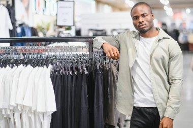 Modern bir moda mağazasında şık bir adam, şık bir alışveriş merkezinde alışveriş deneyiminin tadını çıkarıyor.