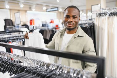 Müşteri şık bir balıkçı yaka kazak seçerken şık bir giyim mağazasına göz atıyor ve modern bir alışveriş deneyiminin tadını çıkarıyor.