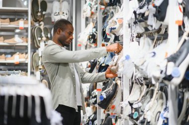 Modern bir ayakkabı mağazasında ayakkabı seçen şık bir adam, perakende deneyiminin tadını çıkarıyor.