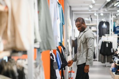 Müşteri giyim mağazasında kıyafet seçiyor, alışveriş deneyiminden zevk alıyor ve yeni kıyafetler arıyor.