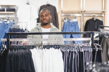 Delikanlı modaya uygun bir mağazada şık kıyafetler seçip gardırobunu geliştirmek için en uygun kıyafeti arıyor.