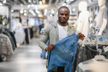 Müşteri şık bir kotla canlı bir moda mağazasında alışveriş yapıyor, moda kıyafetlerin seçiminin tadını çıkarıyor.